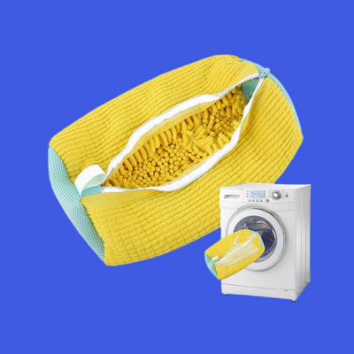 SneakerGlow Chenille Laundry Bag in yellow and grey, open with microfiber interior, next to washing machine.