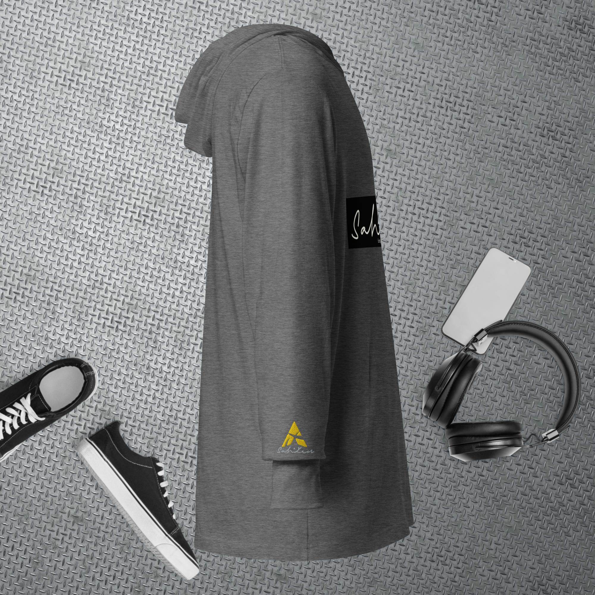 Hooded long-sleeve tee in gray, displayed with black sneakers and headphones on textured background.