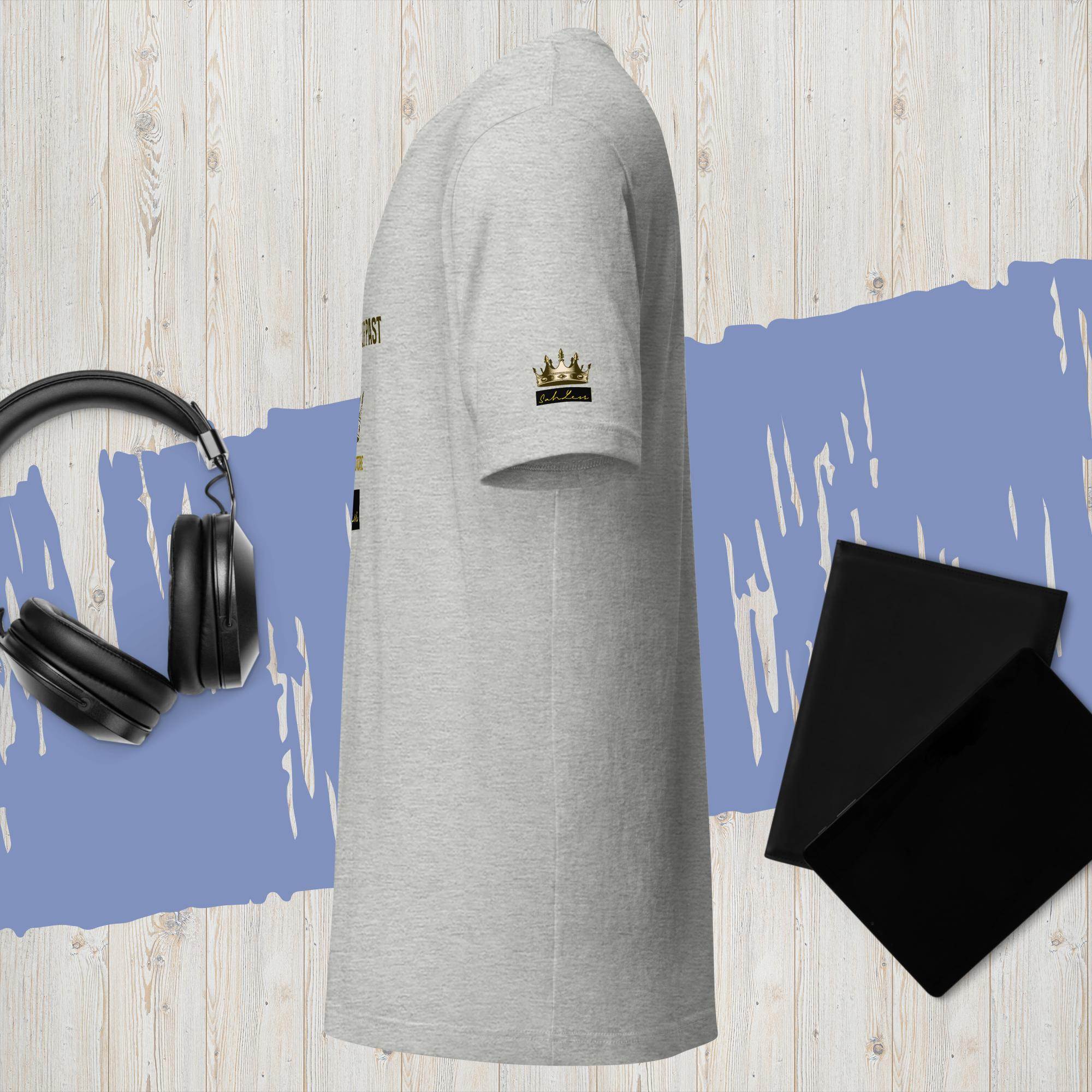 Unisex t-shirt with "SahLess-Don't Let the Past" design, lightweight cotton, in a casual setting with headphones and notebooks.
