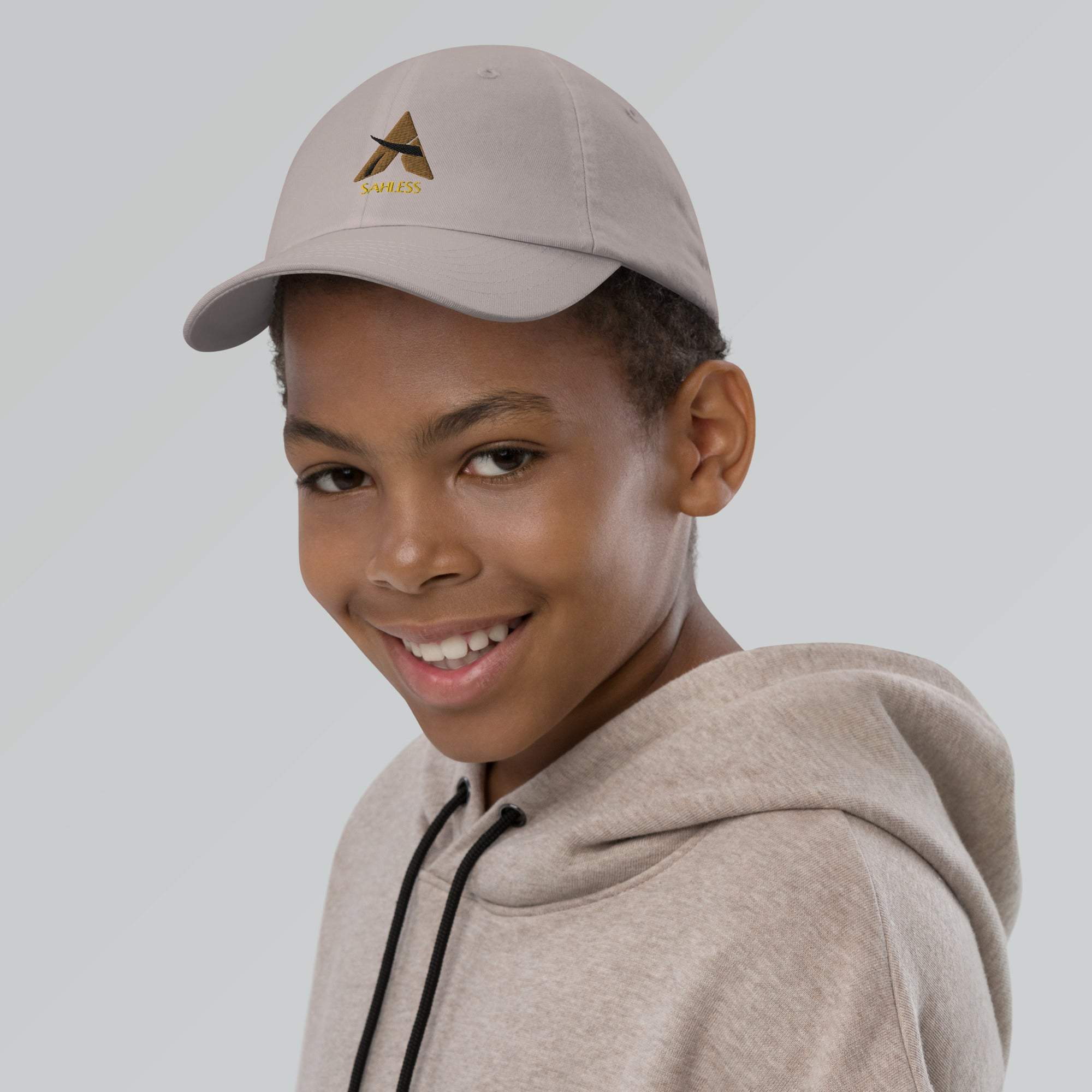 Youth cap baseball in beige worn by smiling child, featuring embroidered logo and adjustable strap for comfort and style.