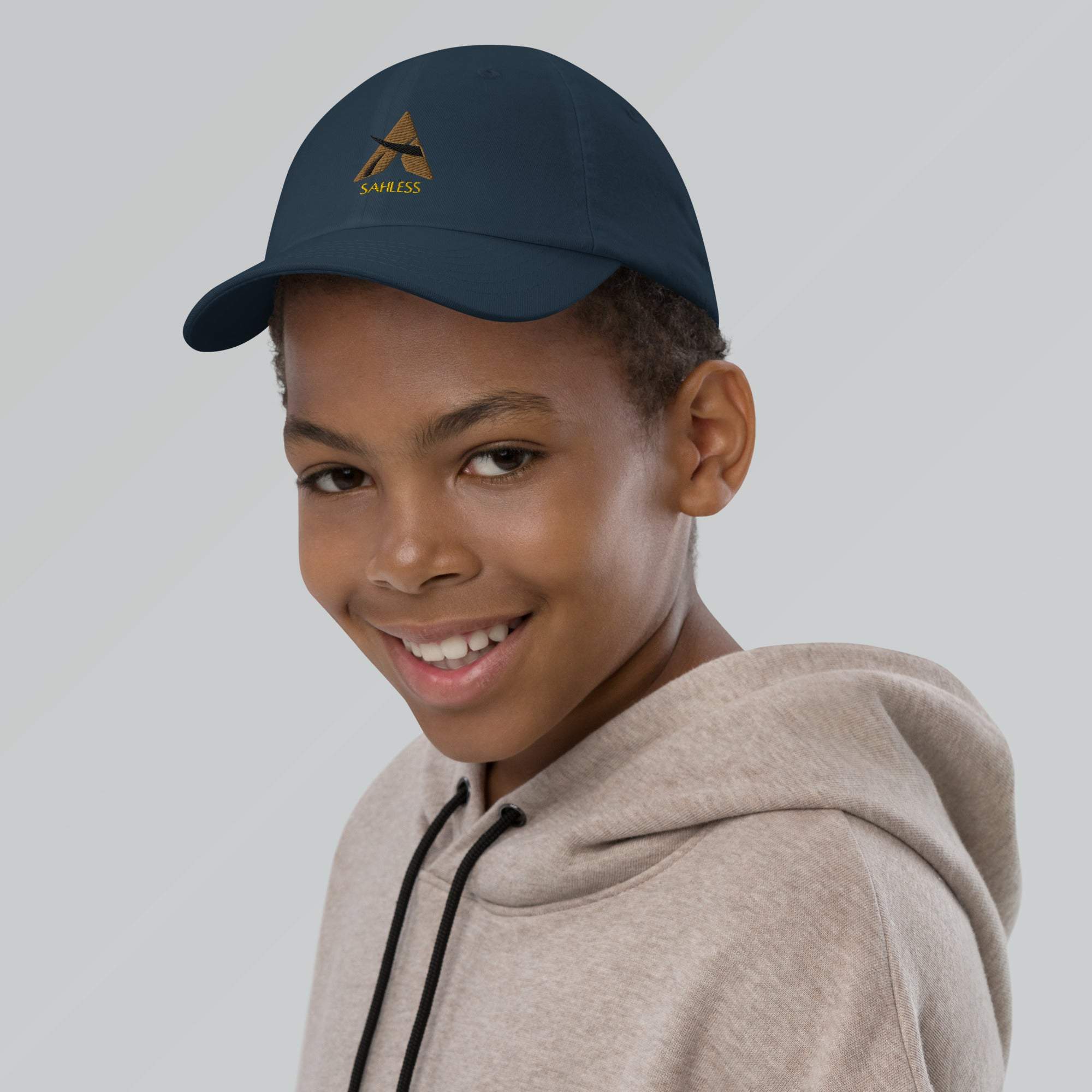 Youth baseball cap with SahLess logo, featuring 6 eyelets, adjustable strap, and pre-curved visor.