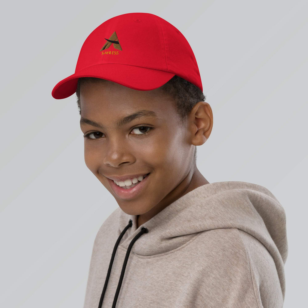 Red SahLess youth baseball cap with adjustable strap worn by a smiling child.